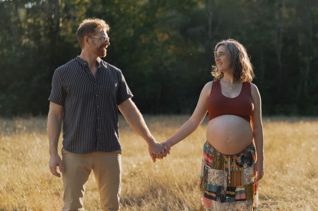 New expecting parents in a field during golden hour