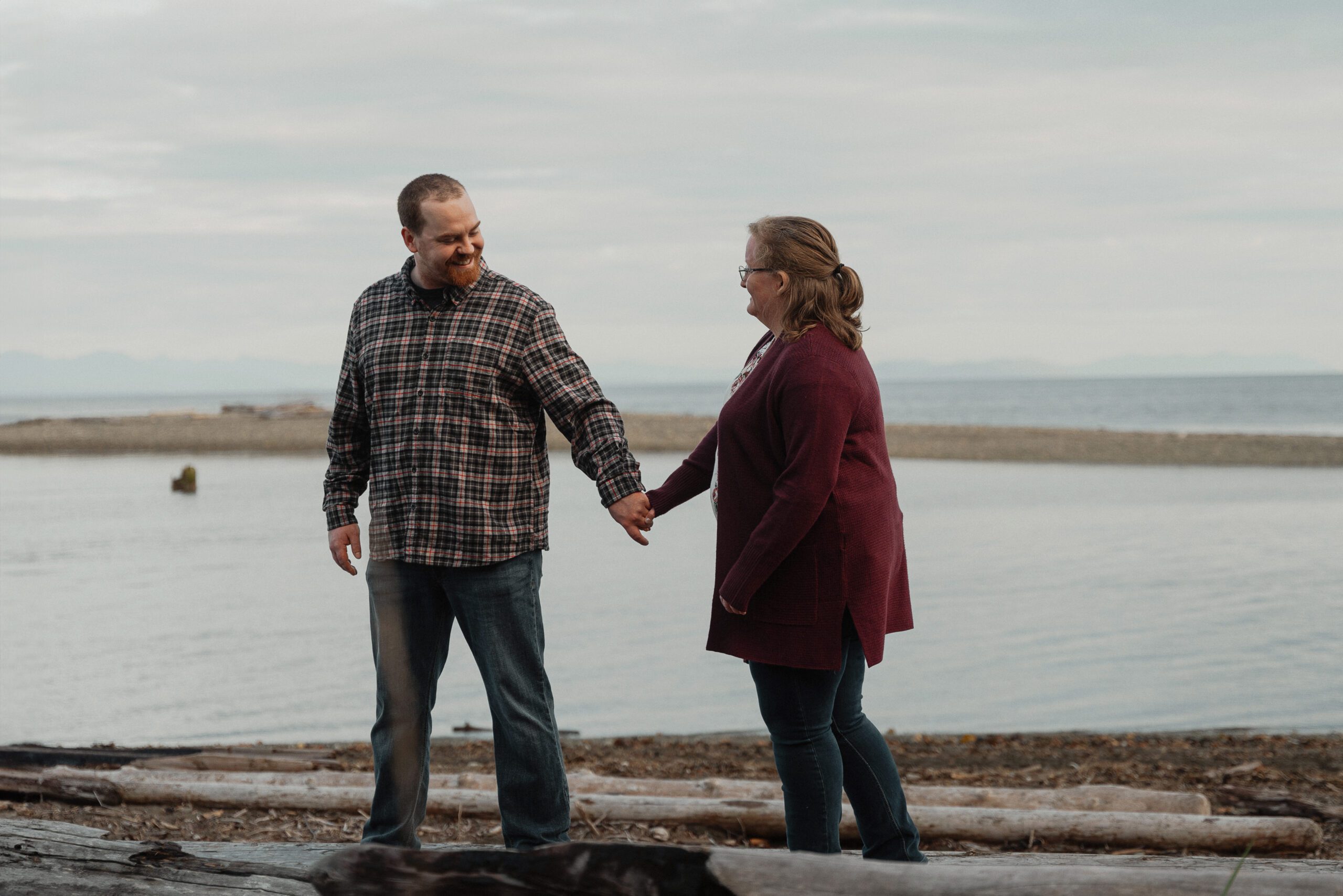 Couple walking on the beach during their engagement session at the Oyster River trails by Latitude 49 photography