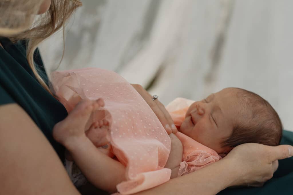 Baby smiling up at mother during relaxed backyard family photoshoot