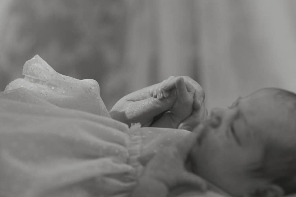 New mom holding baby's hand during a mini motherhood session with Latitude 49 Photography