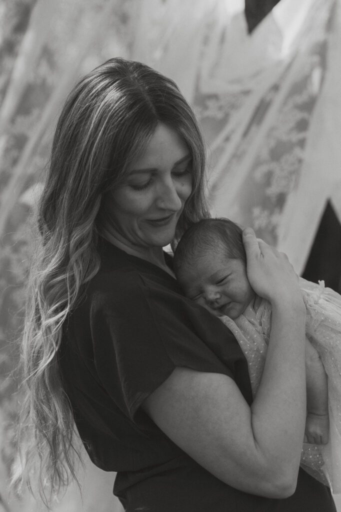 New mom smiling at her baby during cozy backyard motherhood mini session
