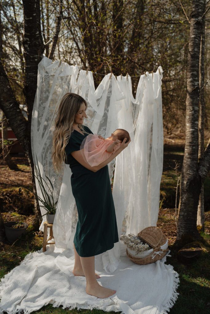 New mom smiling at her baby during cozy backyard motherhood mini session