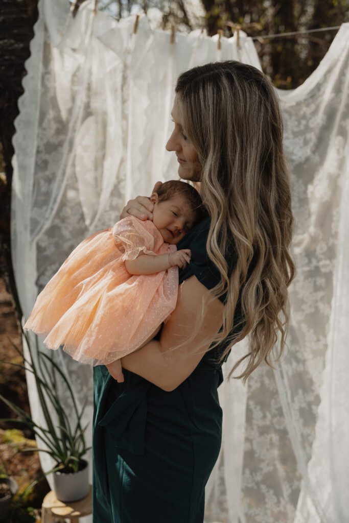 Mother cuddling newborn outdoors in natural light on Vancouver Island