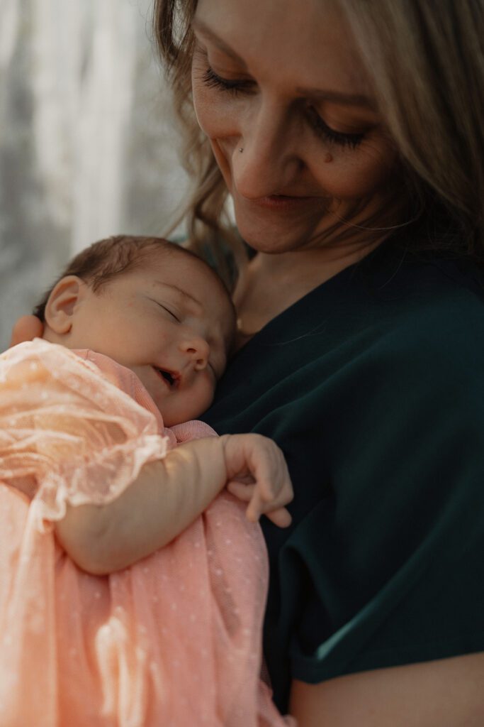 New mom smiling at her baby during cozy backyard motherhood mini session