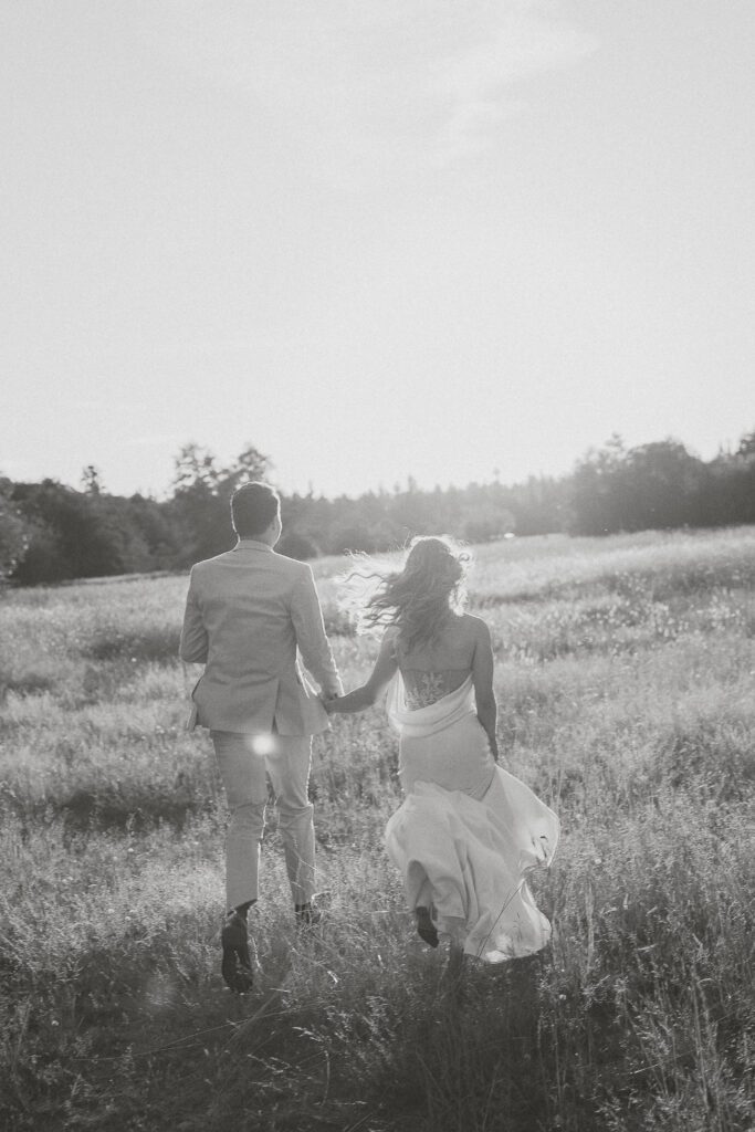 Couple running in a field during their wedding portraits by Latitude 49 Photography