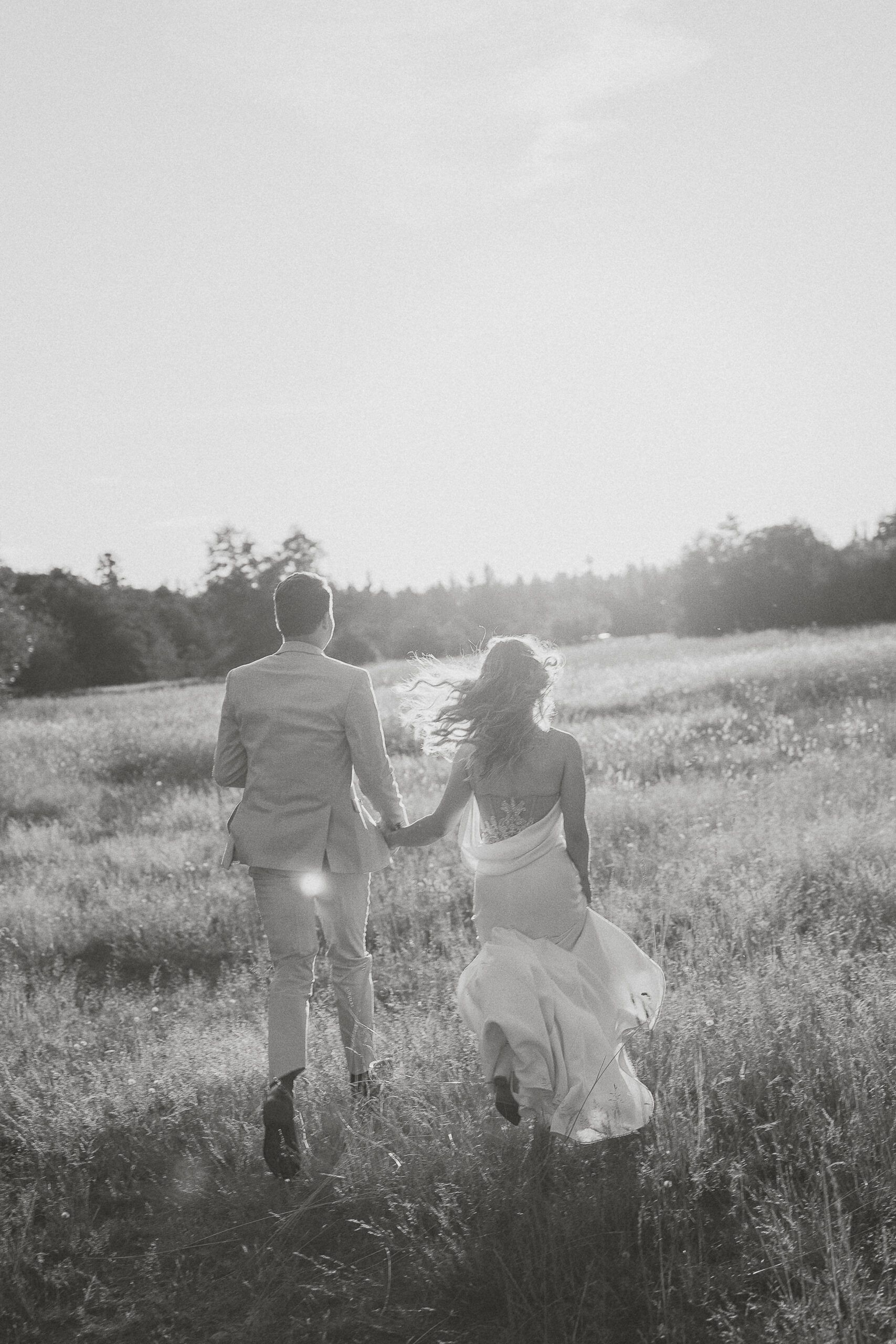 Couple running in a field during their wedding portraits by Latitude 49 Photography