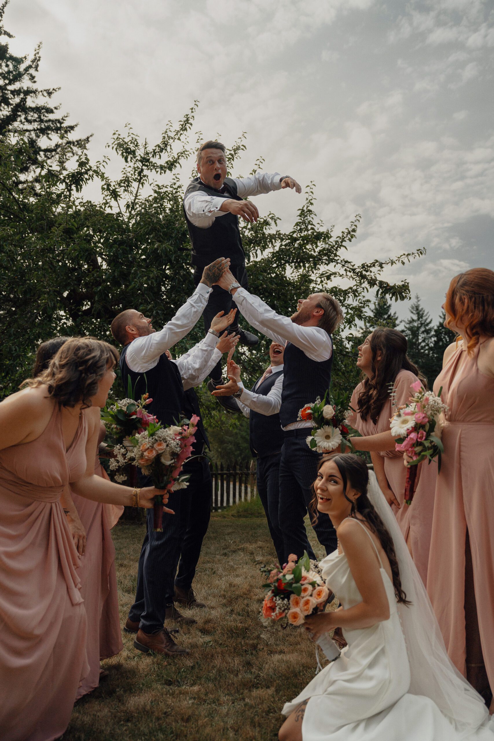 wedding party throwing groom into the air during wedding portraits in Victoria