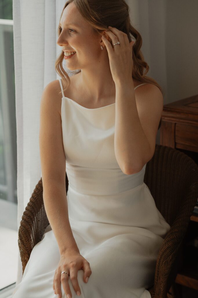 Bride in wedding dress sitting during getting ready photos by latitude 49 photography in Saanichton