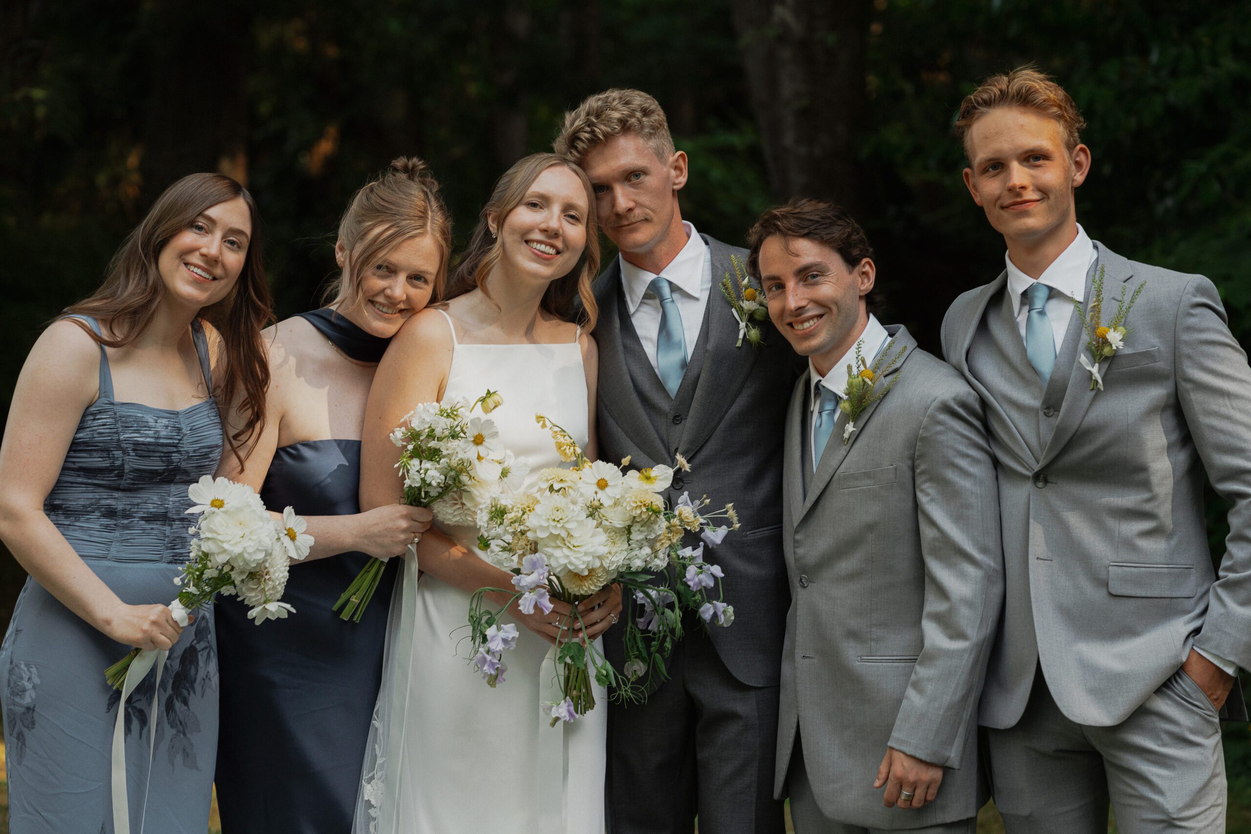 Wedding party huddled in together during wedding party portraits at Heritage Acres in Saanichton by Latitude 49 Photography