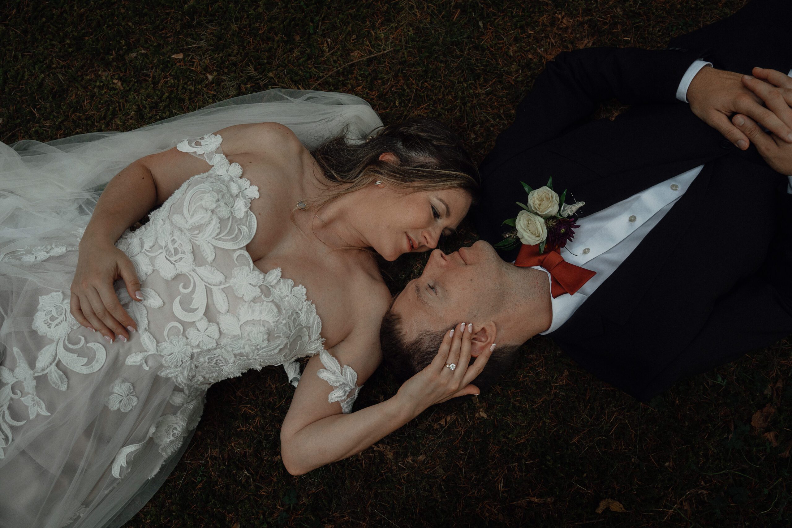 bride and groom laying on the mossy grass at Kitty Coleman Woodland Gardens by Latitude 49 Photography