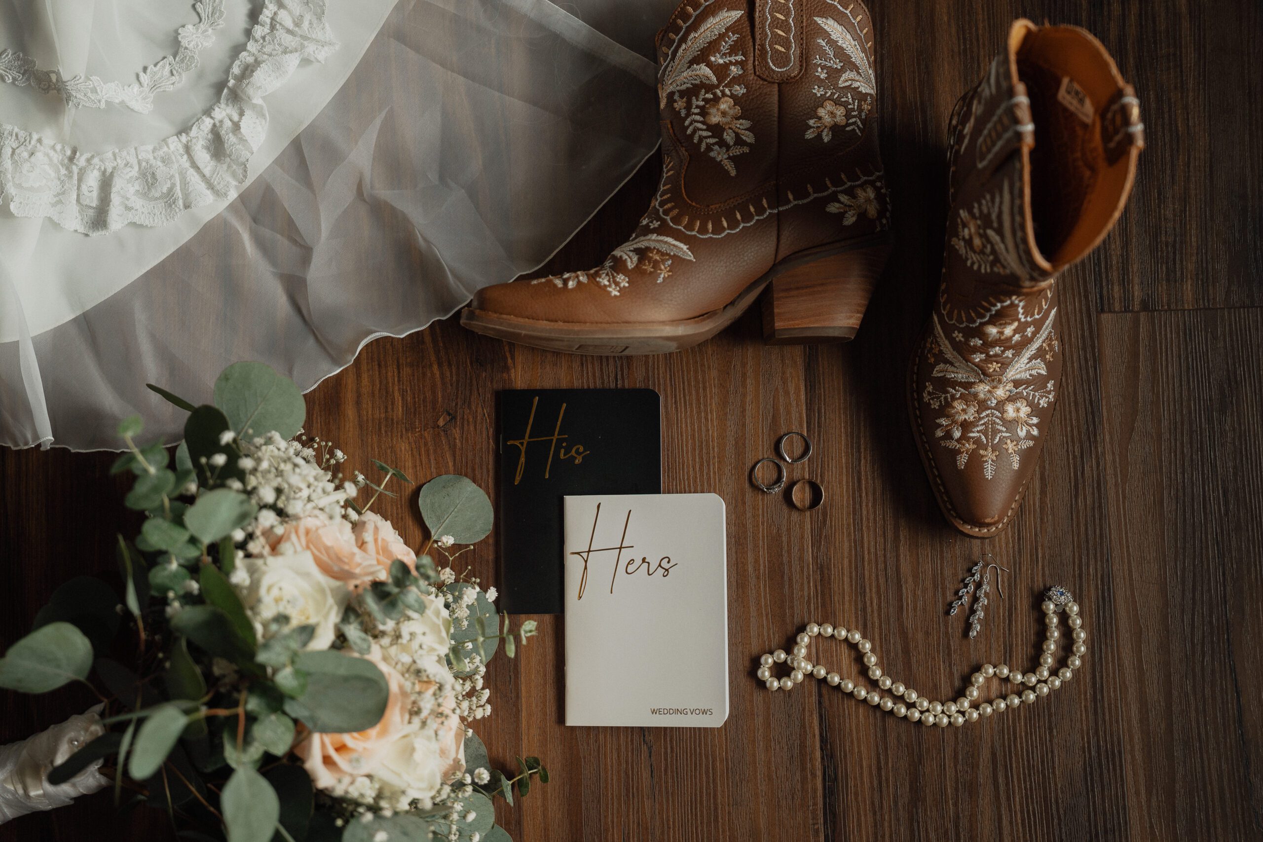 wedding details photo including cowboy boots, dress and bouquet during getting ready photos by latitude 49 photography