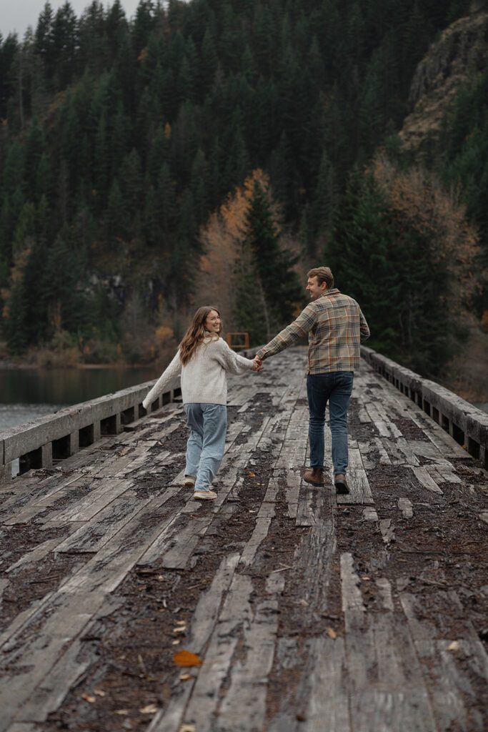 connor and liz running during their fall engagement session at the Trestle Bridge in Campbell River.