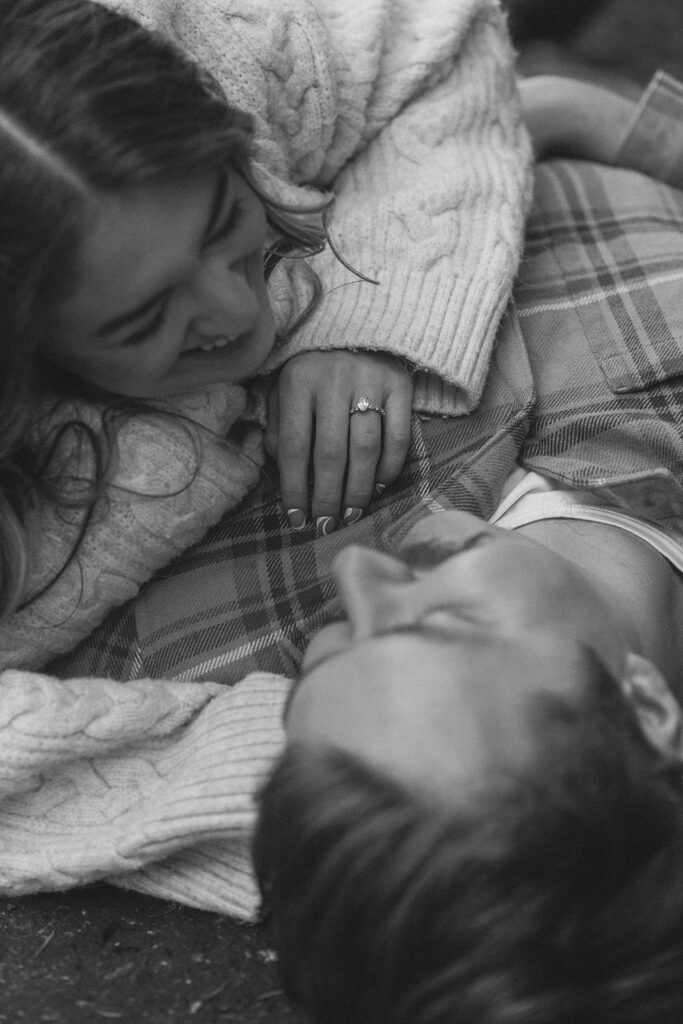 Black and white photo of Liz and Connor laying on the ground during their fall engagement session at the Trestle Bridge in Campbell River.