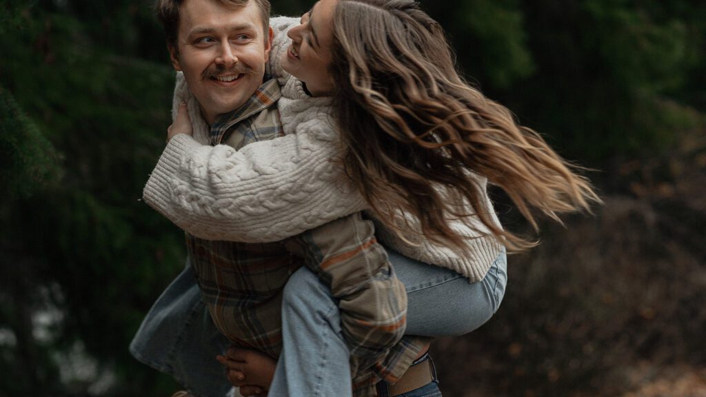 Connor piggybacking Liz during their fall engagement session at the Trestle Bridge in Campbell River.