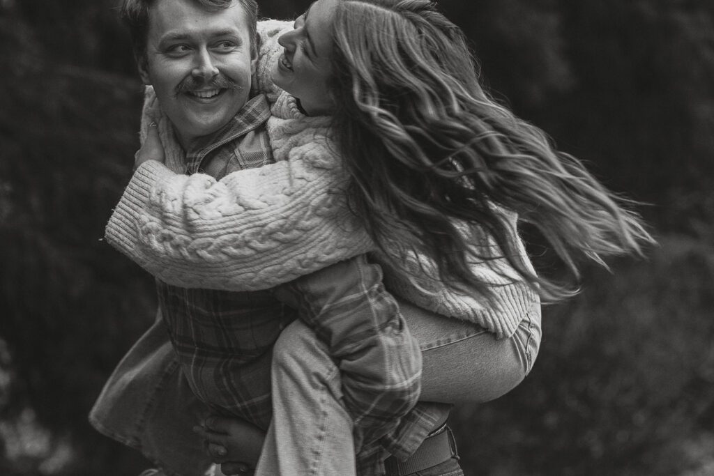 Connor piggybacking liz and swinging around during their fall engagement session at the Trestle Bridge in Campbell River.
