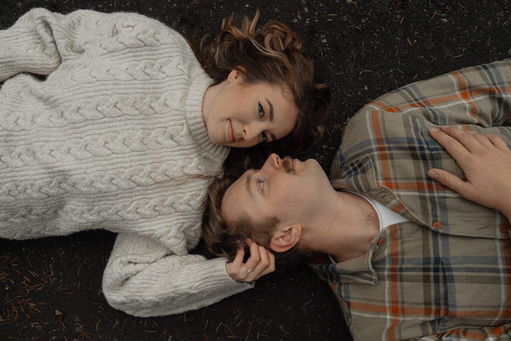 Liz and connor laying down for photos during their fall engagement session at the Trestle Bridge in Campbell River.