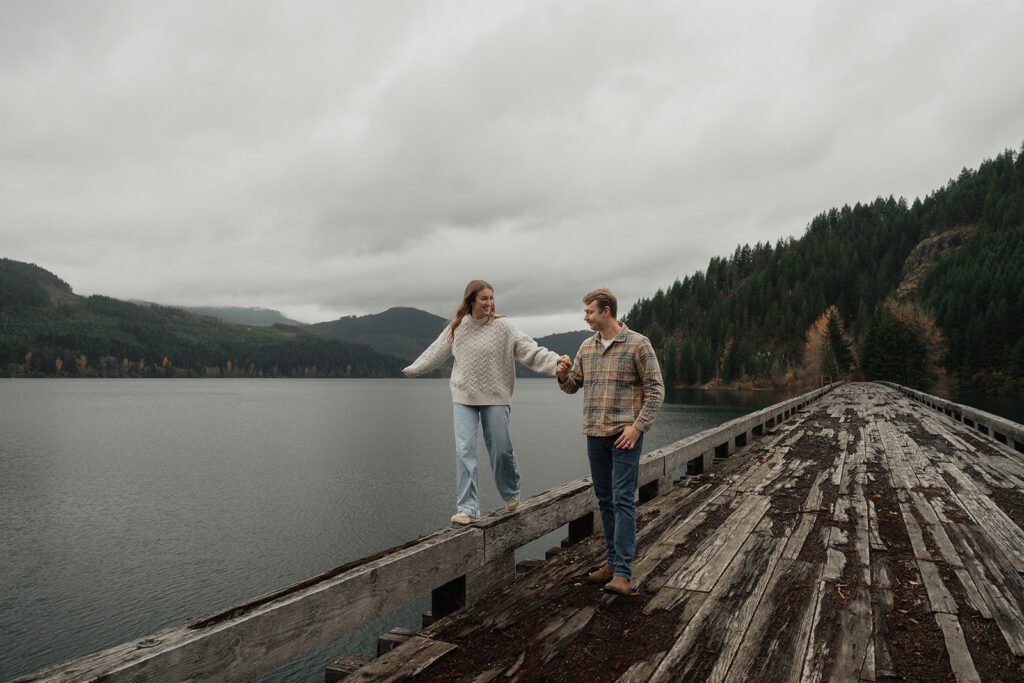 Liz walking on the bridge and connor holding her hand during their fall engagement session at the Trestle Bridge in Campbell River.