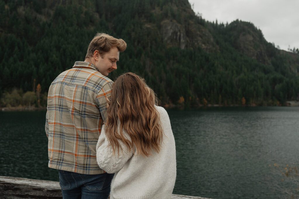 Connor and liz looking out at the lake during their fall engagement session at the Trestle Bridge in Campbell River.