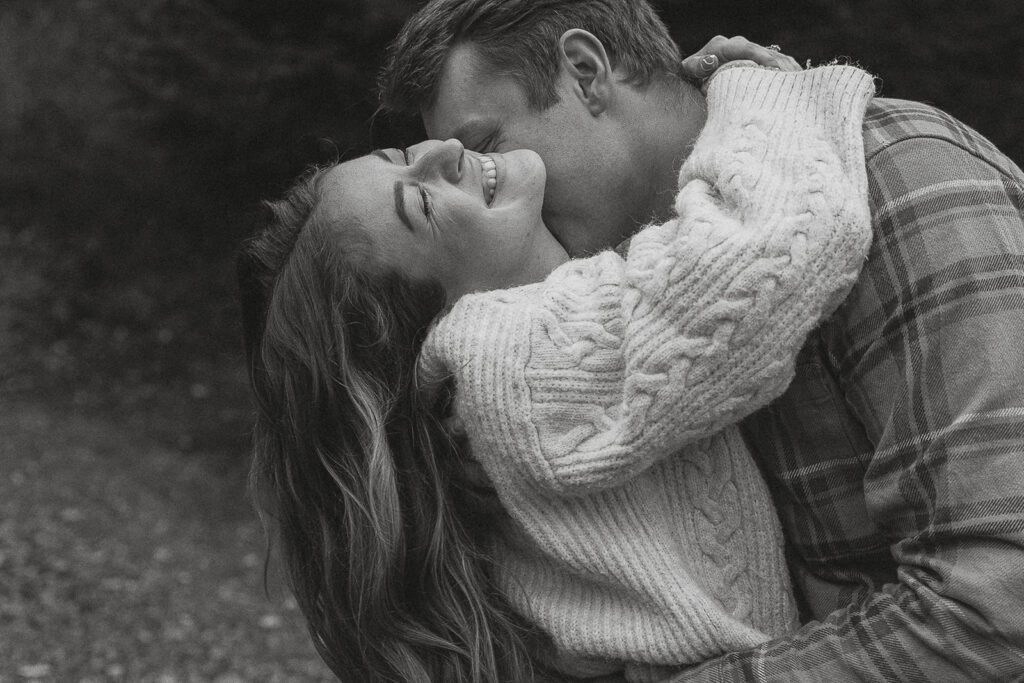 black and white photo of Connor kissing Liz during their fall engagement session at the Trestle Bridge in Campbell River.