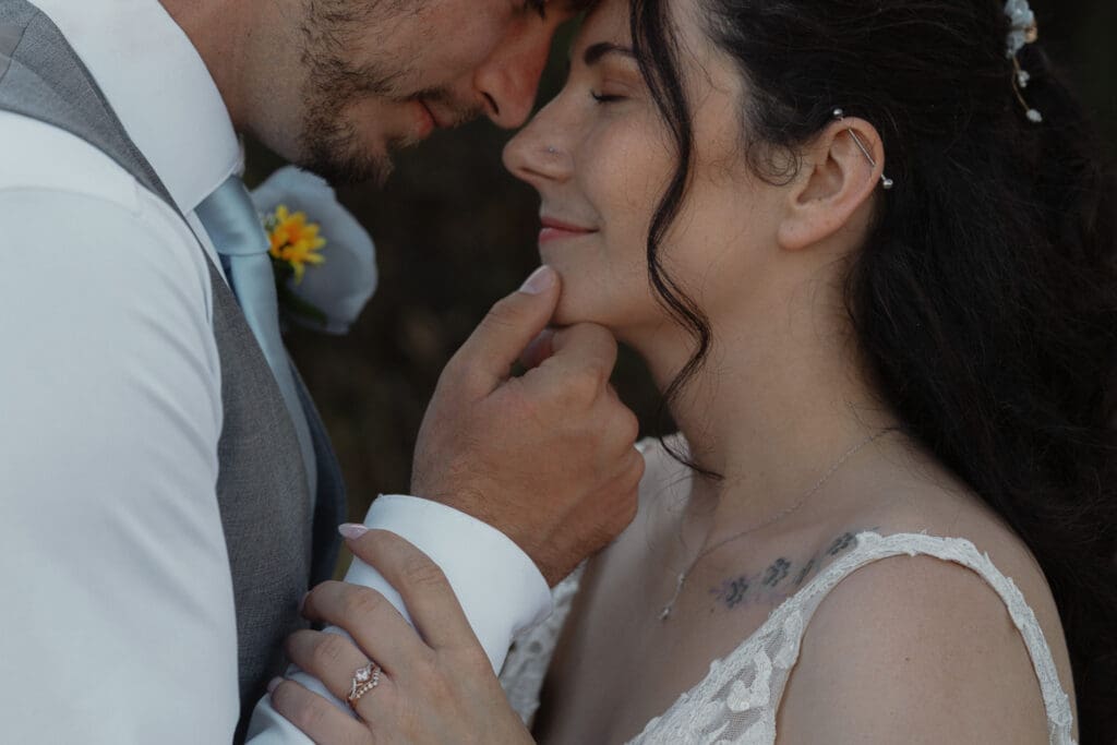 Couple touching foreheads during their wedding portraits at Airforce Beach by latitude 49 photography