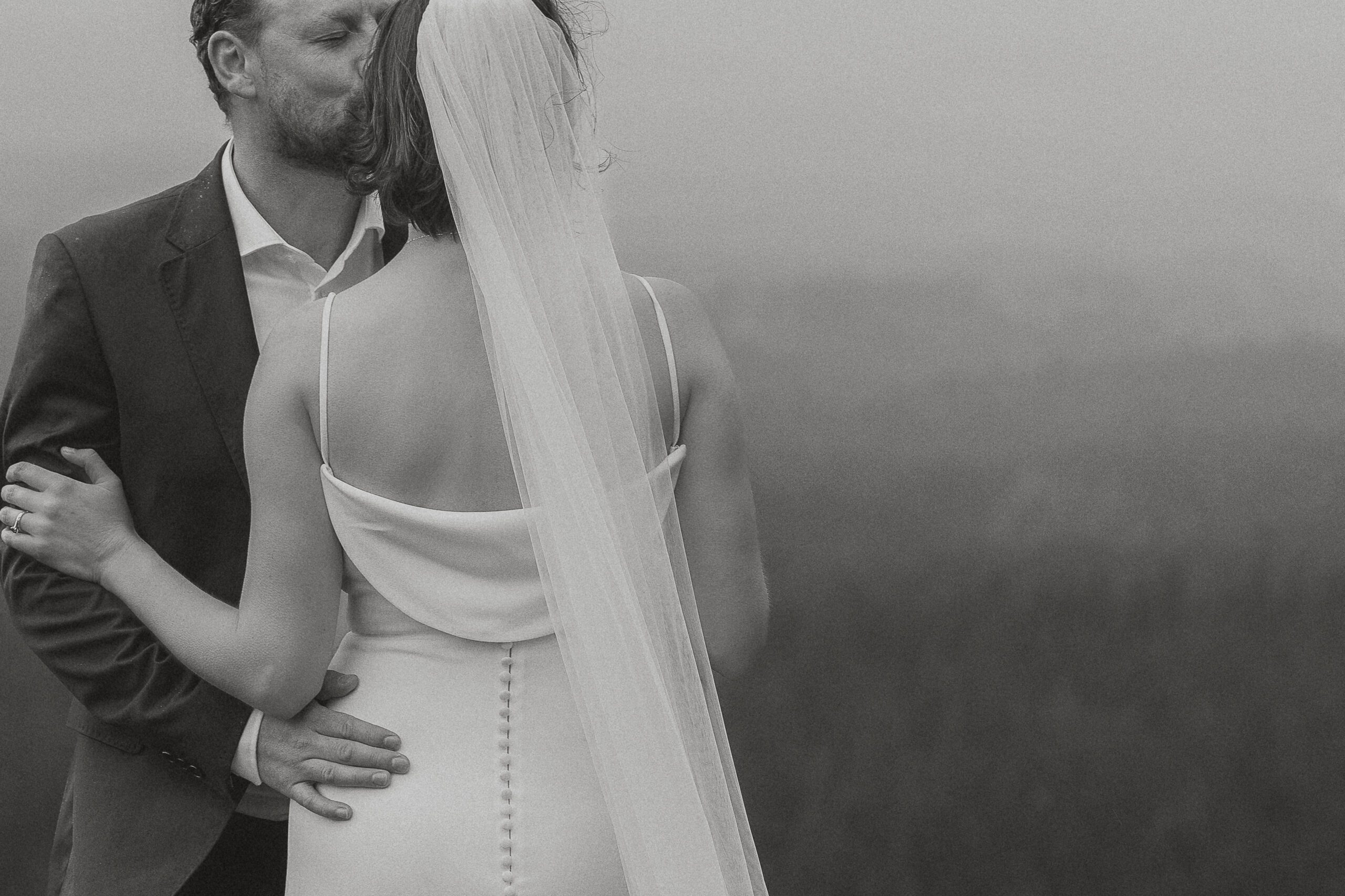 Groom kissing bride on the cheek overlooking Little Mountain in Errington by Latitude 49 Photography