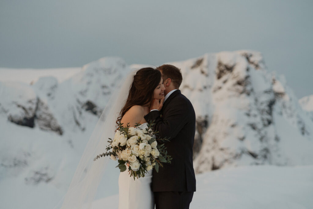 Bride and groom share a moment in front of a glacier at their elopement