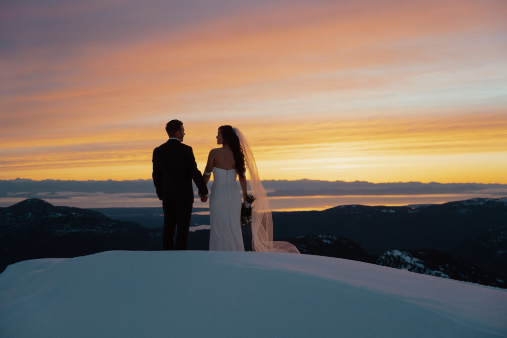 bride and groom watching the sunrise during their mountaintop elopement