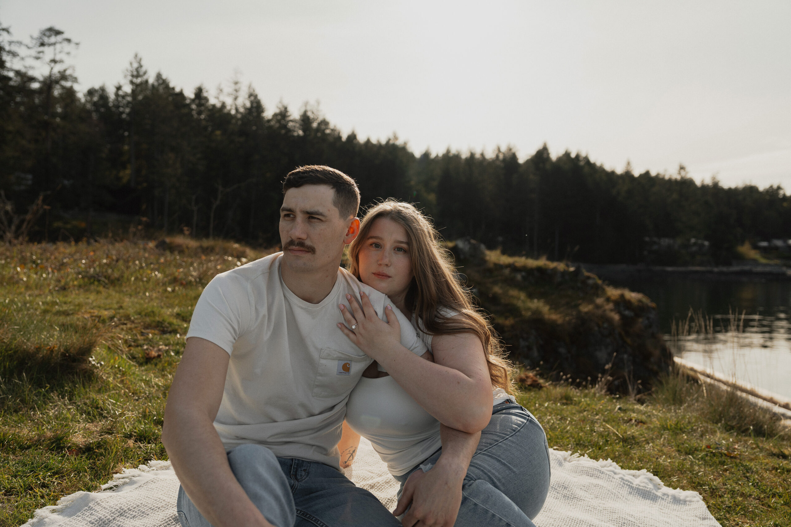 Engaged couple looking over the ocean views at Es-hw Sme~nts Community Park in Nanoose bay